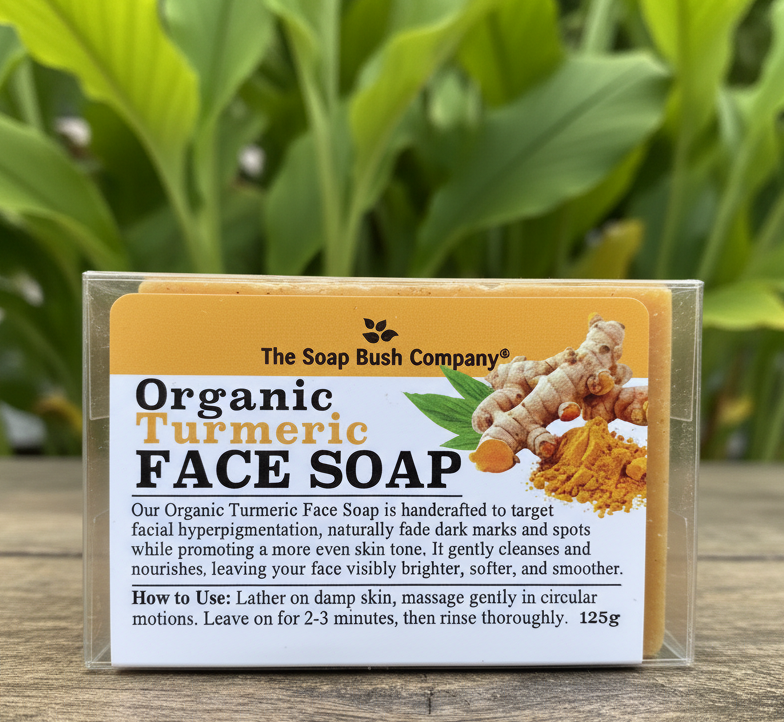 Organic turmeric face soap packaging with text on a wooden surface and green leafy background, the soap bush company organic turmeric face soap, clore beauty supply, targets facial hyperpigmentation, naturally fade dark marks and spots
